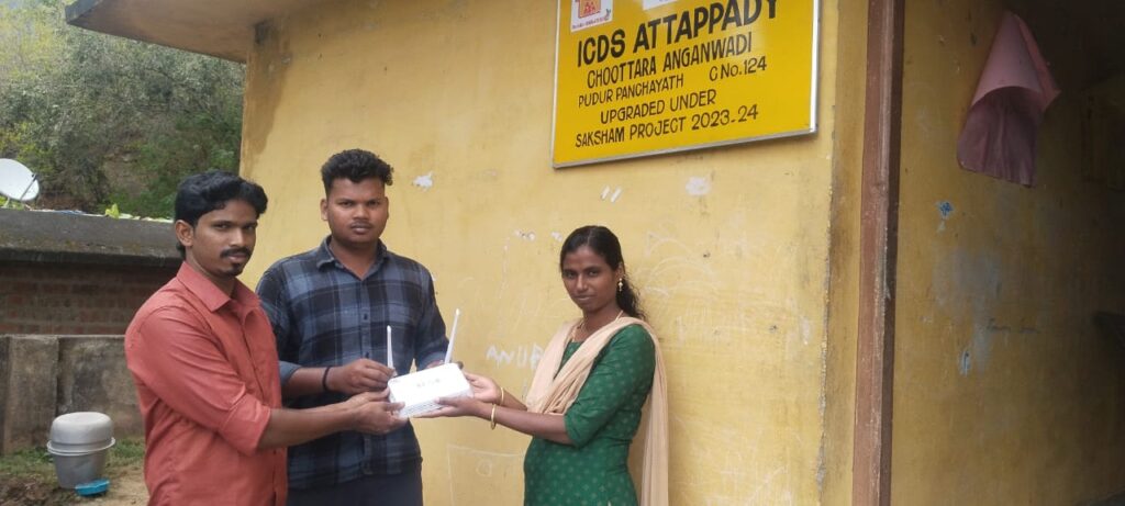 Representatives from Attappadi Cable Vision hand over a KFON Wi-Fi modem to the teacher at Chootra Anganwadi in Pudoor Grama Panchayat
